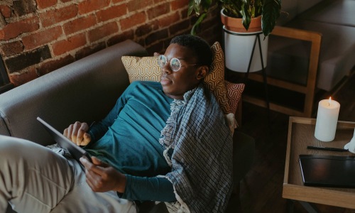 a man looks at his tablet while lying on his living room couch